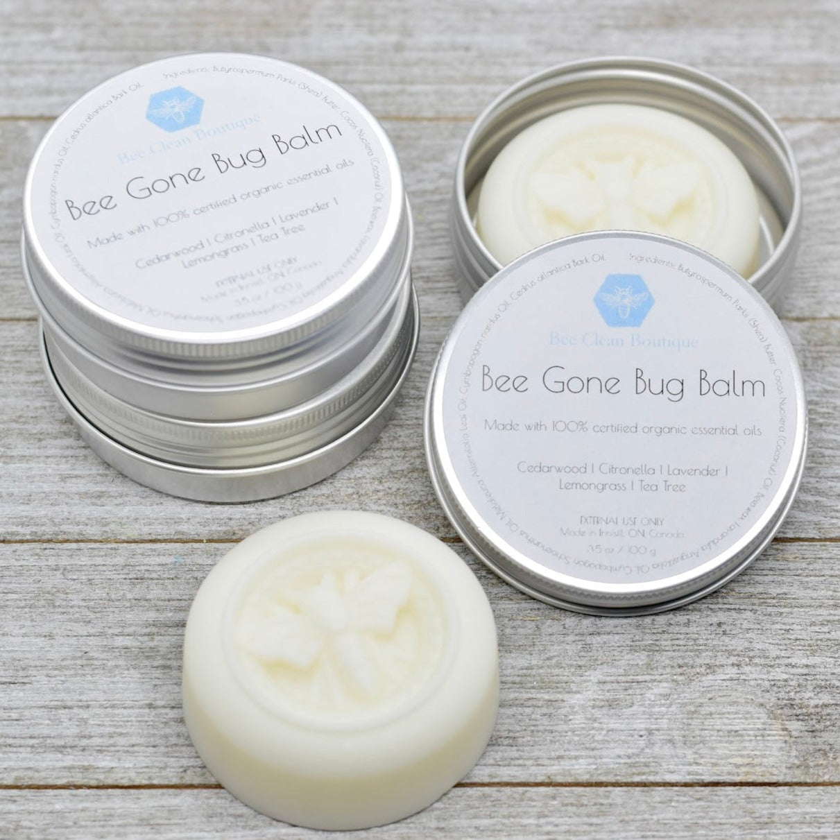 Tins of Bee Gone Bug Balm on display on a wooden surface