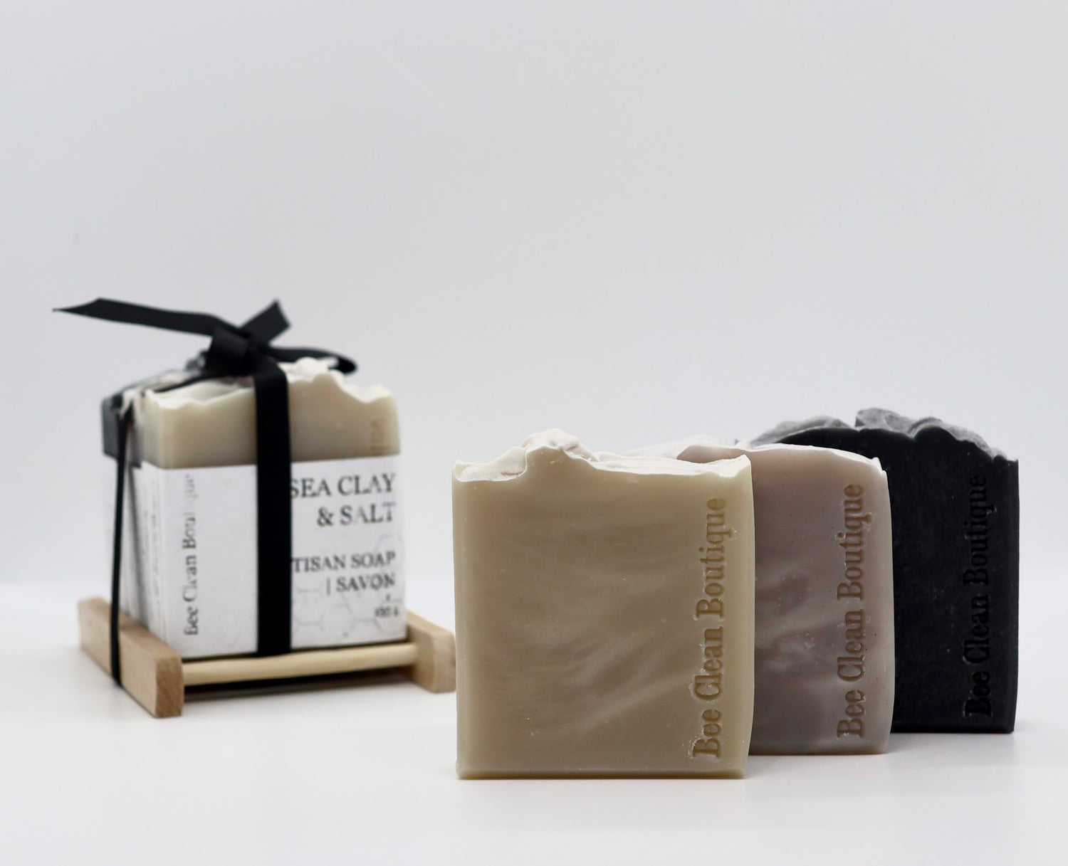 Set of 3 handmade soaps for men, displayed individually and also in a bundle tied with black ribbon on a wooden soap dish