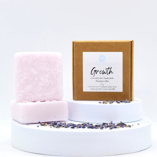 Growth shampoo bars are on a white tiered display decorated with lavender seeds, a labelled kraft box is also displayed